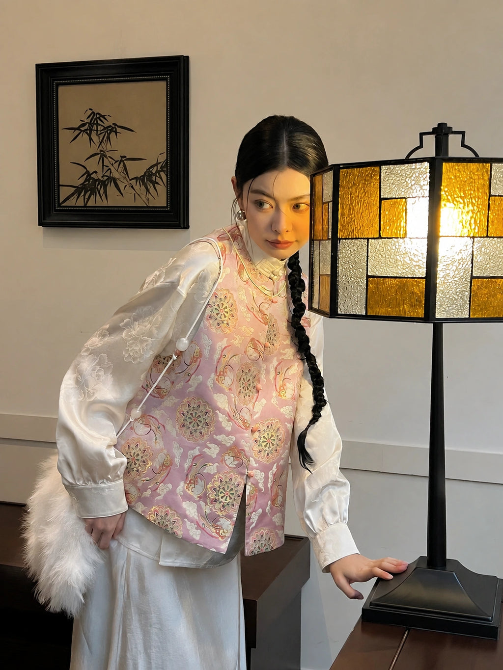 Close styling view of the Jade Rabbit Song brocade silk vest with gold-thread motifs under warm light