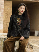 Seated model wearing the Jianwu stand-collar jacket with a floral appliqué and curved front corners