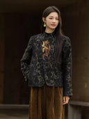 Close view of the jacket showing its dark floral weave, multicolored embroidered appliqué, and gold-tone cuff buttons