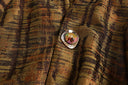 Close-up of the jacket’s decorative round button against the brown and dark plaid fabric.