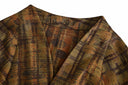 Close-up of the jacket’s V-shaped neckline and softly blurred brown plaid pattern.