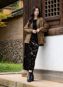 Full-length view of the open plaid jacket styled over a black top and dark patterned skirt.