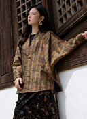 Model wearing the V-neck plaid jacket with one arm extended beside a wooden window.