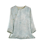 Front product view of a light blue Hualuo jacquard silk blouse with a round neck, asymmetric buttons and three-quarter sleeves