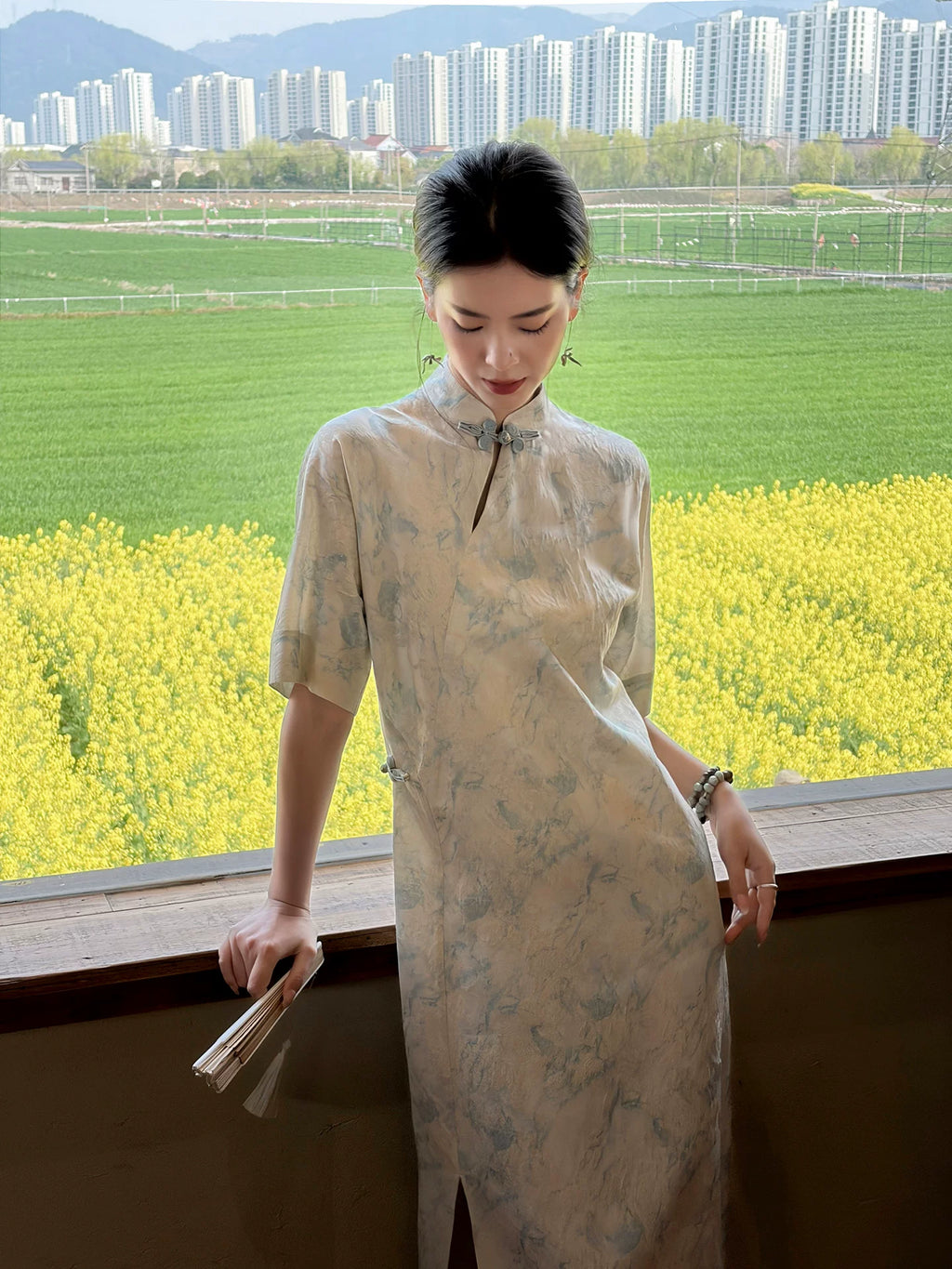 Woman wearing a light blue mandarin collar dress overlooking a spring countryside landscape