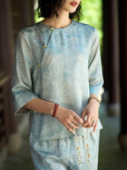 Close-up of a light blue jacquard silk blouse with an asymmetric decorative button placket