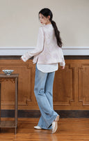 Back styling view of the pink vest layered over a white top with blue jeans.