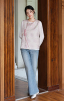 Back styling view of the pink vest layered over a white top with blue jeans.