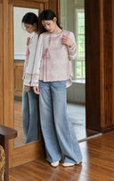 Model beside a mirror wearing the pink vest, white inner top and wide-leg jeans.