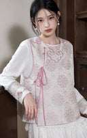 Close styling view of the vest’s ruyi-inspired neckline, pink piping and side tie.