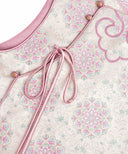 Close-up of the vest’s pink tie, decorative buttons and floral-medallion pattern.