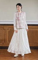 Full-length look of the pink jacquard vest over a white inner top with a flowing white skirt.