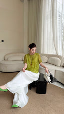 Sitting woman in a lime green round neck top with short sleeves, showcasing the comfortable fit and soft viscose-polyester blend fabric.