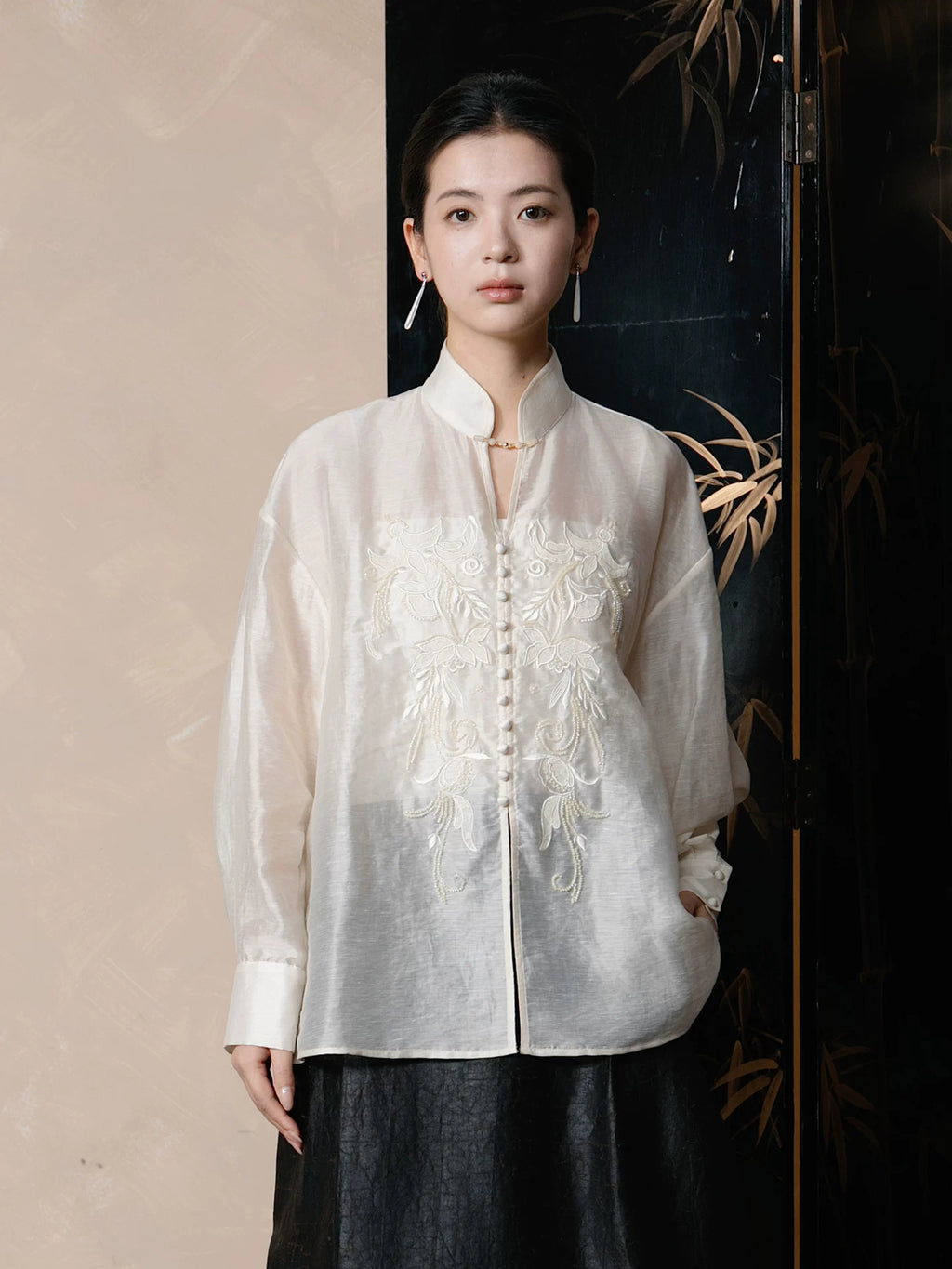 Women's mandarin collar lyocell linen blend blouse with elegant floral embroidery and covered buttons.