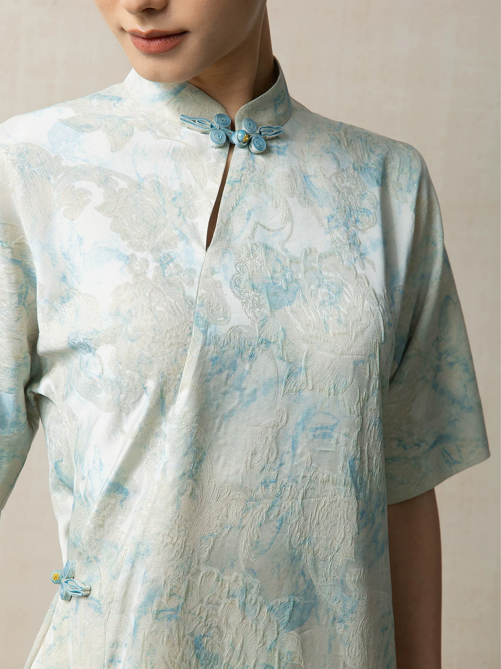 Close-up of the handcrafted frog buttons and mandarin collar on a light blue jacquard dress