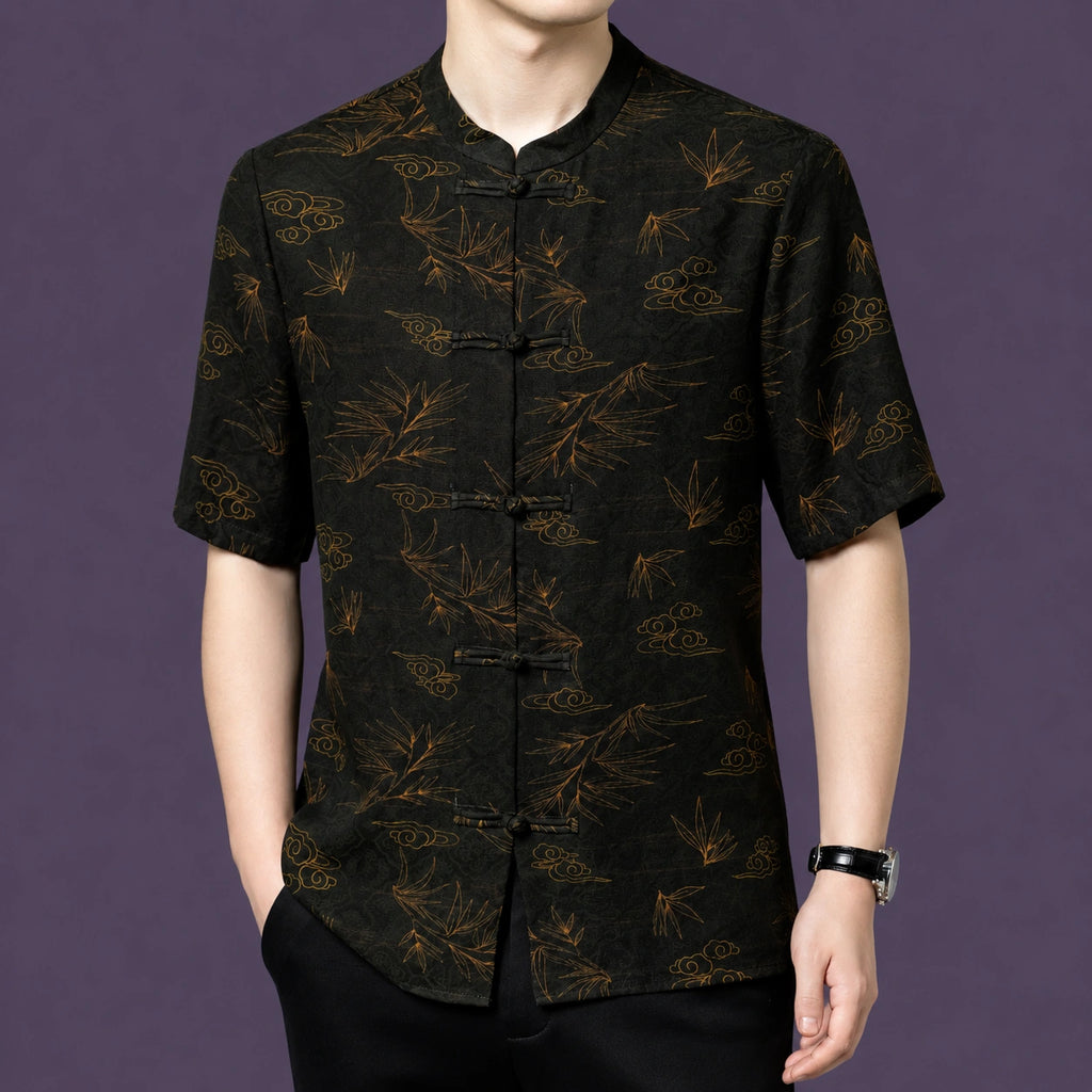 Men's black silk short-sleeve shirt with a stand collar and vintage-inspired traditional print, styled with black trousers and a watch.