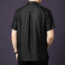 Back view of the black silk shirt, highlighting the natural drape and a central pleat detail at the back yoke.