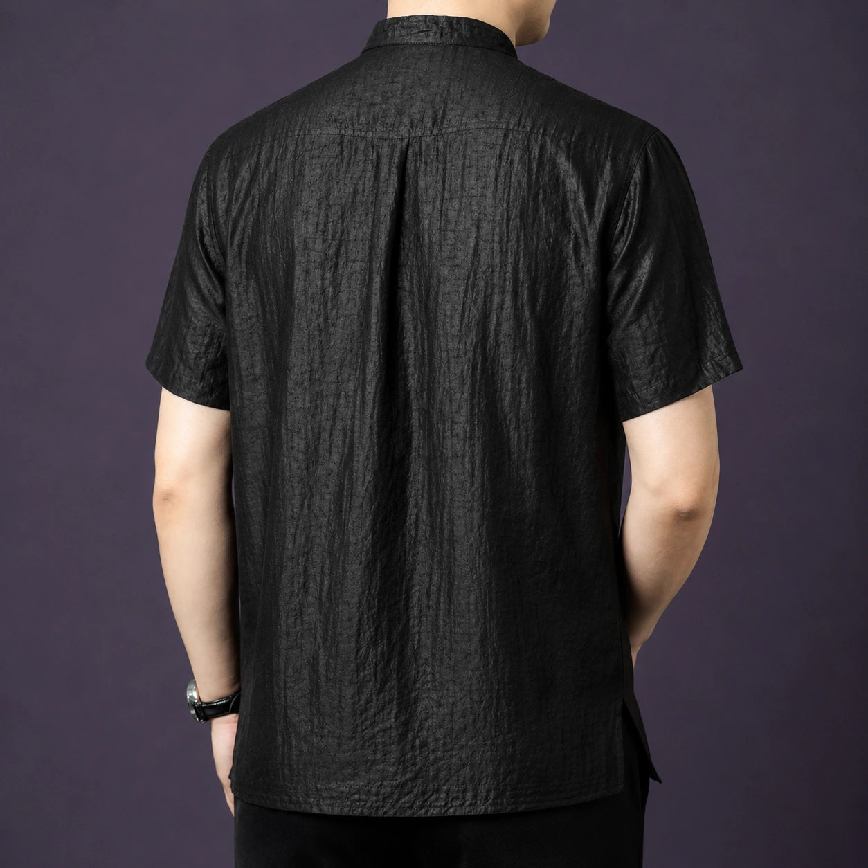 Back view of the black silk shirt, highlighting the natural drape and a central pleat detail at the back yoke.