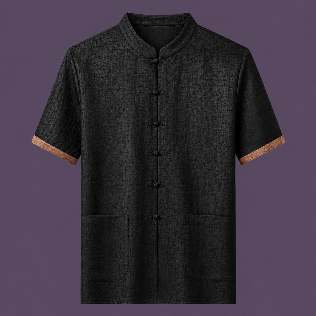 Flat lay of the men's short-sleeve silk top, featuring a stand collar, six front frog buttons, two patch pockets, and distinctive brown cuffs.