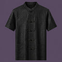 Flat lay of the men's black silk short-sleeve shirt, showing the stand collar, embroidered frog buttons, and three front pockets.