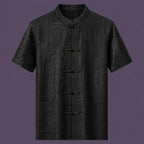 Flat lay of the men's black silk short-sleeve shirt, showing the stand collar, embroidered frog buttons, and three front pockets.