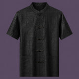 Flat lay of the men's black silk short-sleeve shirt, showing the stand collar, embroidered frog buttons, and three front pockets.