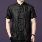 Men's black 100% mulberry silk short-sleeve shirt featuring a textured crackle finish, a stand collar, and delicate embroidered frog buttons down the front placket.