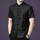 Front view of the black silk top showcasing the intricate embroidery detailing on the frog button placket and three patch pockets.