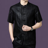Close-up of the black silk shirt highlighting the unique cracked surface texture and the contrasting jacquard pattern along the front placket.