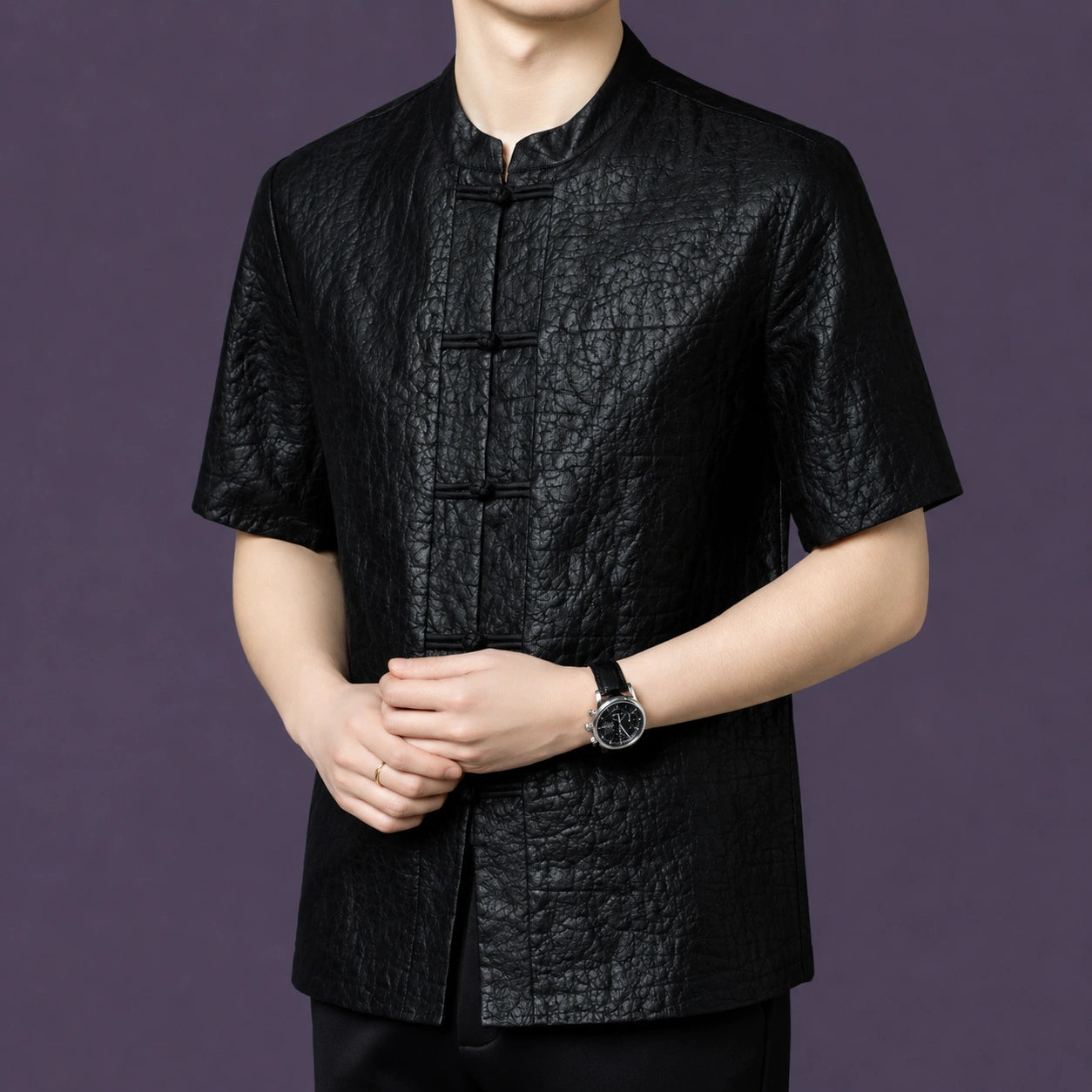 Men's relaxed-fit black silk top with a mandarin collar and frog button closure, styled with black trousers and a watch.