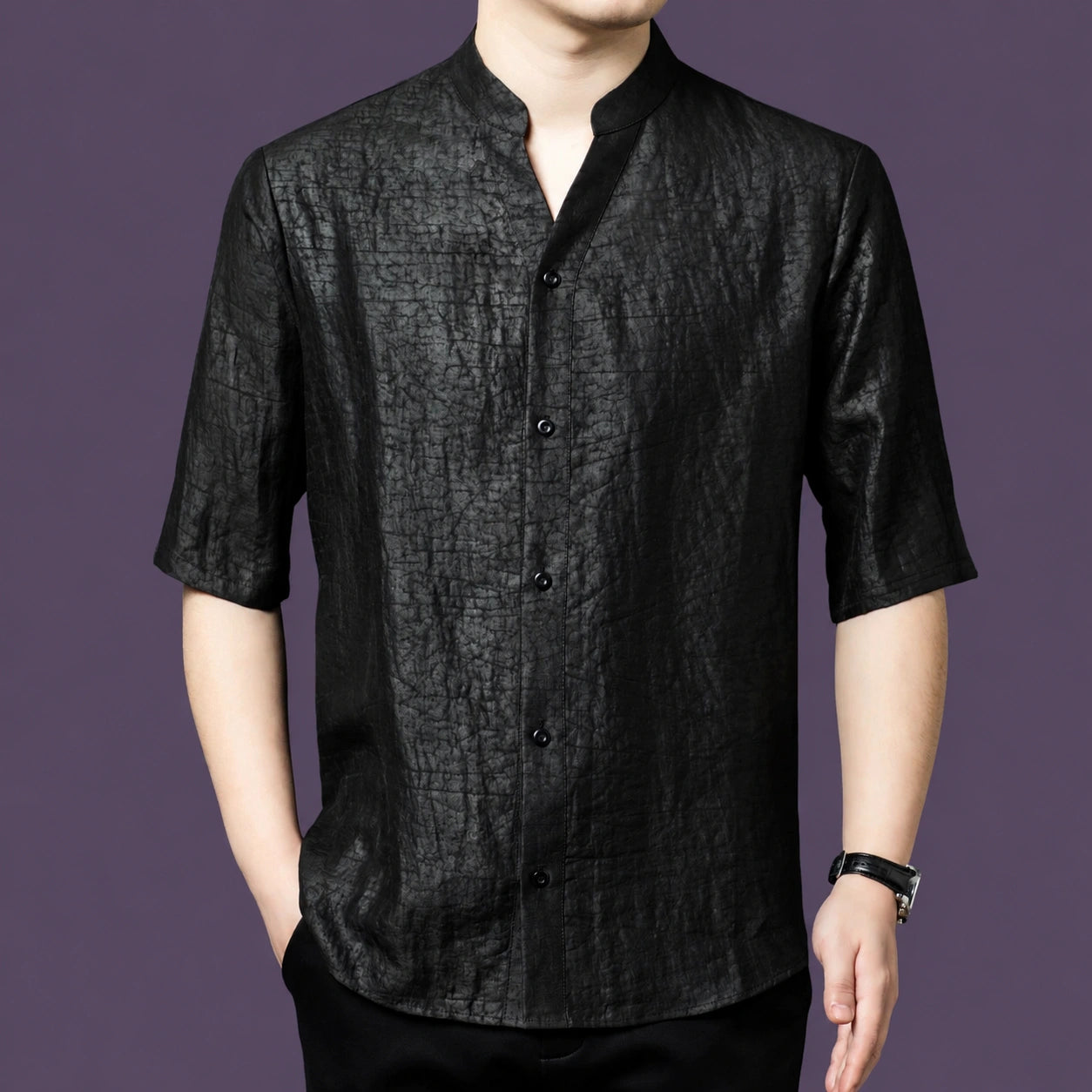 Men's black textured silk top with a simple stand collar and V-neckline, styled with black trousers and a watch.