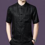 Men's black 100% mulberry silk short-sleeve shirt with a subtle jacquard pattern, a stand collar, traditional frog buttons, and a single chest pocket.