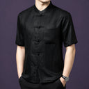 Front view of the black silk top, highlighting the geometric weave texture and the classic frog button placket.