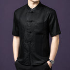 Front view of the black silk top, highlighting the geometric weave texture and the classic frog button placket.