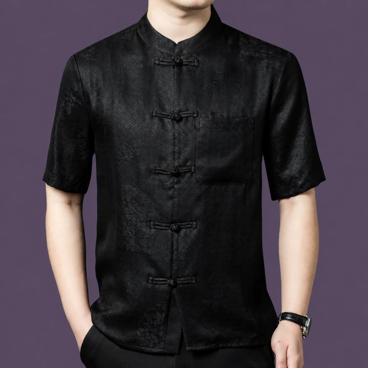 Men's black silk shirt with a relaxed cut and a left-side patch pocket, styled with black trousers and a watch.
