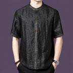 Men's black 100% mulberry silk short-sleeve shirt with a stand collar and contrast amber-colored front buttons, styled with black trousers.