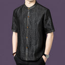 Men's black silk short-sleeve top featuring a unique cracked surface texture and a row of warm-toned buttons along the placket.