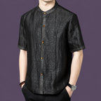 Men's black silk short-sleeve top featuring a unique cracked surface texture and a row of warm-toned buttons along the placket.