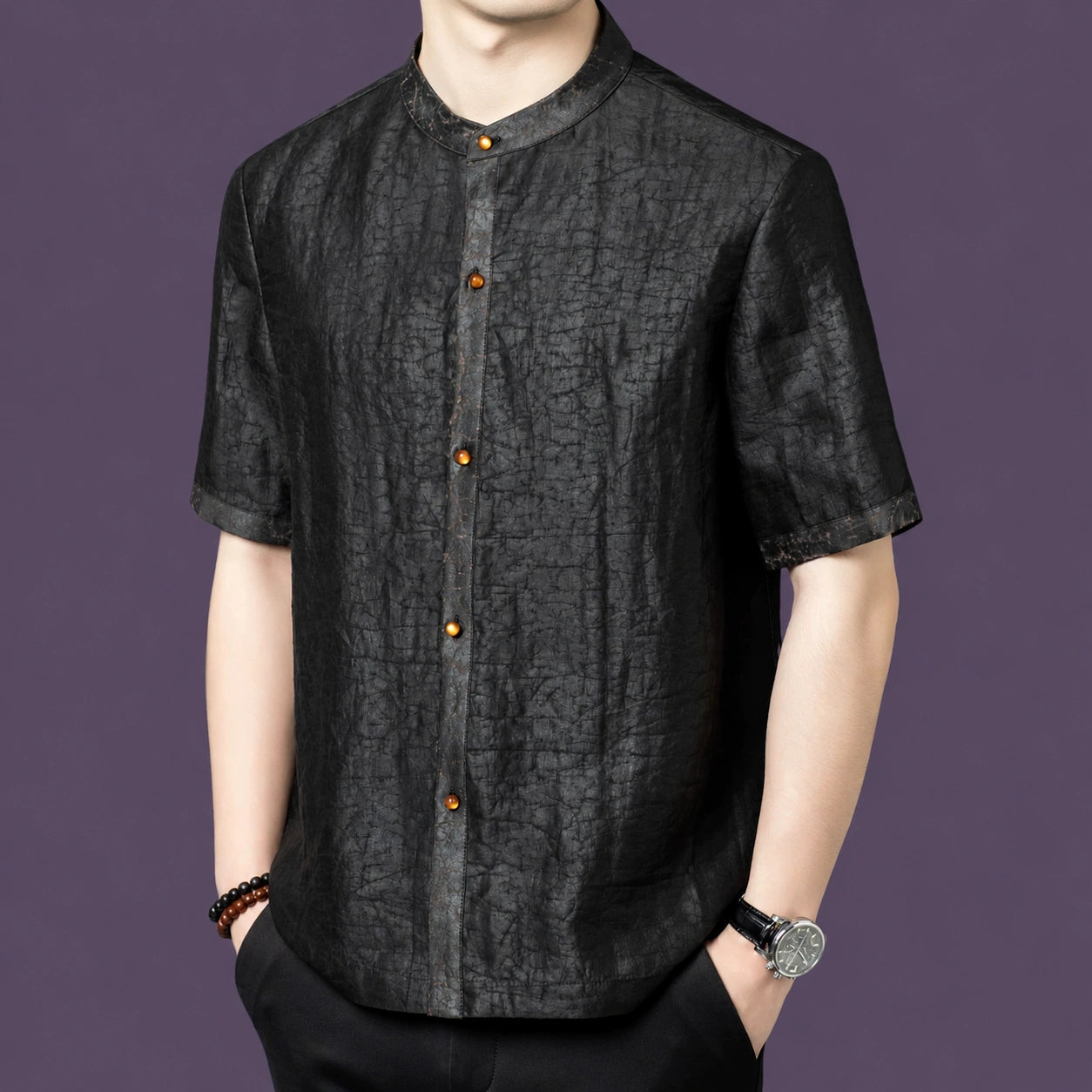 Men's black silk short-sleeve top featuring a unique cracked surface texture and a row of warm-toned buttons along the placket.