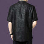 Back view of the men's black silk shirt, showing the straight, relaxed silhouette and the continued cracked texture across the back panel.
