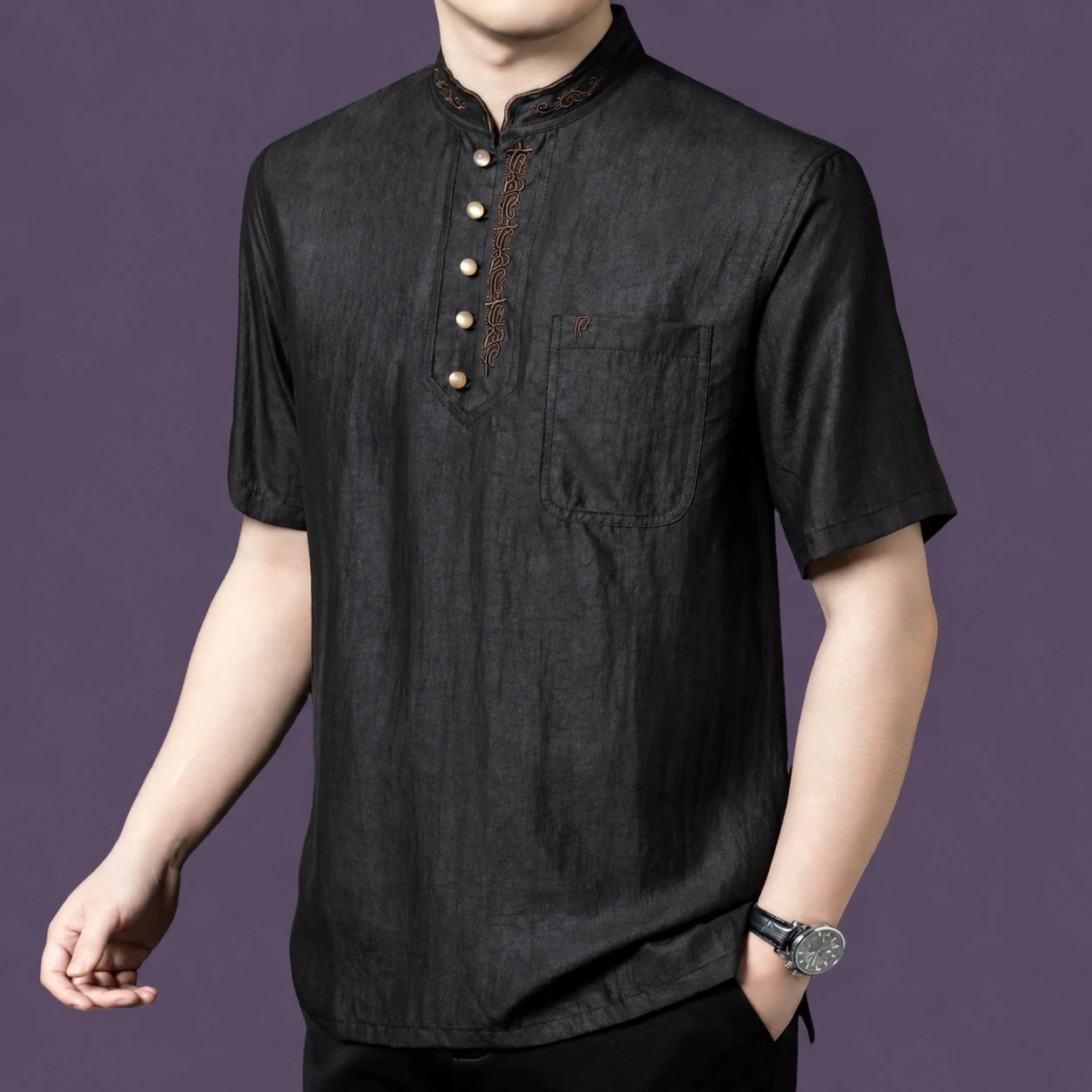 Men's black textured silk shirt with a henley collar and contrasting embroidered trim along the neckline, styled with a watch.