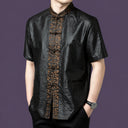 Front view of a black silk shirt with a textured body and a detailed embroidered jacquard panel running down the center.