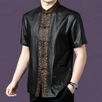 Men's black silk short-sleeve shirt with patch pockets and an ornate bronze jacquard placket, styled with a watch and black trousers.