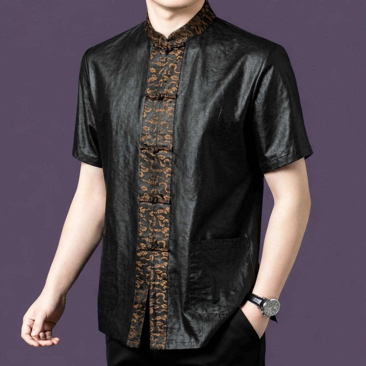 Men's black silk short-sleeve shirt with patch pockets and an ornate bronze jacquard placket, styled with a watch and black trousers.