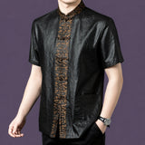 Men's black silk short-sleeve shirt with patch pockets and an ornate bronze jacquard placket, styled with a watch and black trousers.