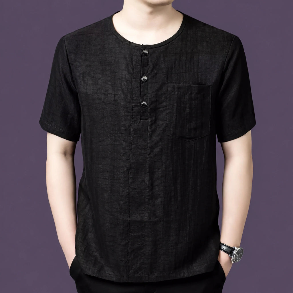 Men's black 100% mulberry silk short-sleeve henley shirt with a round neck, 3-button placket, and single chest pocket, styled with black trousers.