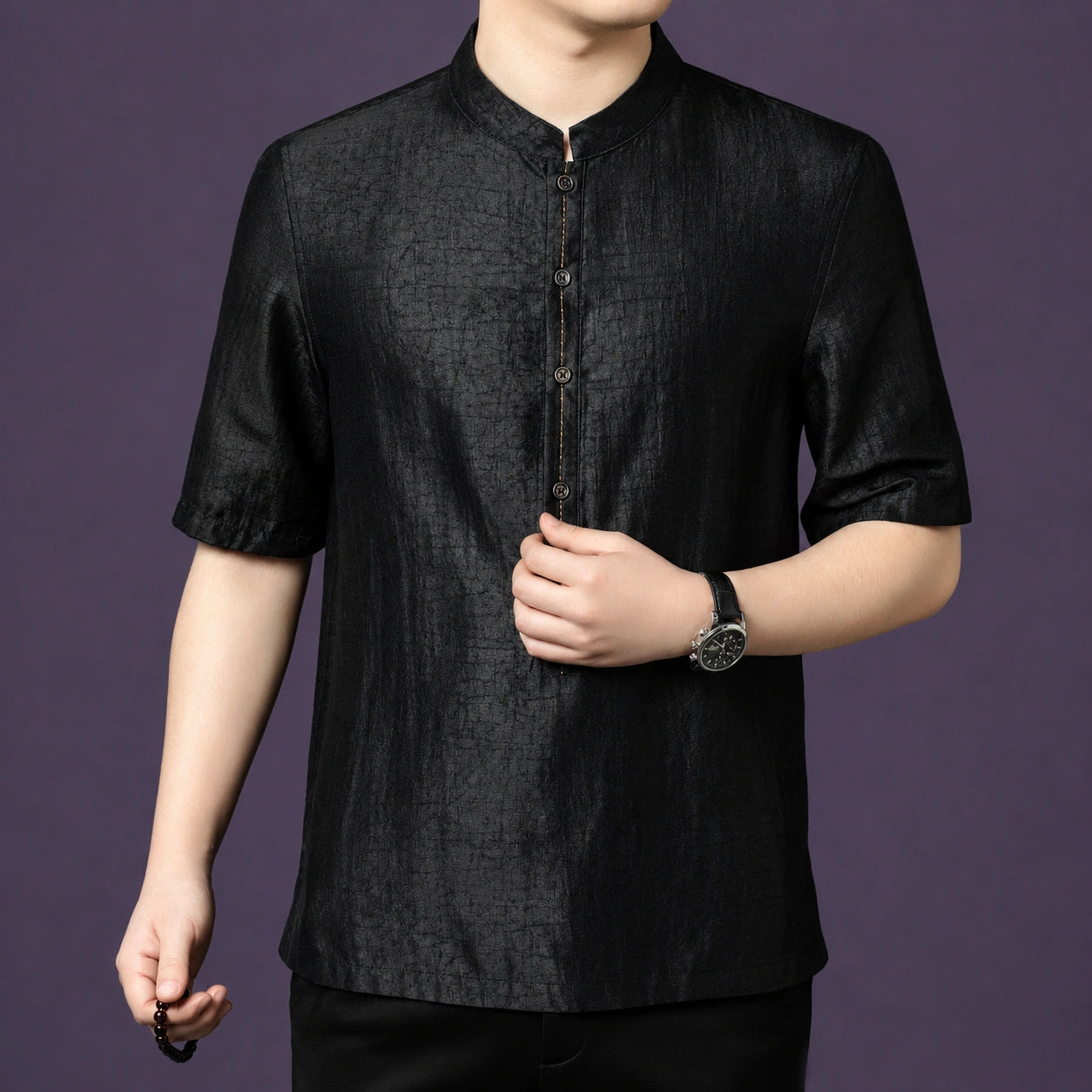 Close-up of the black silk shirt, showing the fine stitching details along the front placket and button accents.