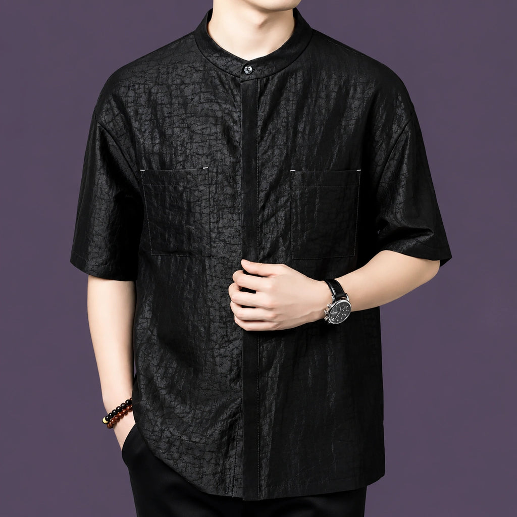 Men's black silk short-sleeve shirt with a mandarin collar and practical front pockets, styled with black trousers and a watch.