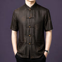 Men's dark brown 100% mulberry silk short-sleeve shirt featuring a traditional stand collar, geometric jacquard base pattern, and round wooden frog buttons.