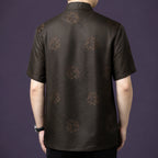 Back view of the dark brown silk shirt, showcasing the consistent geometric jacquard weave and scattered floral motifs across the entire fabric.